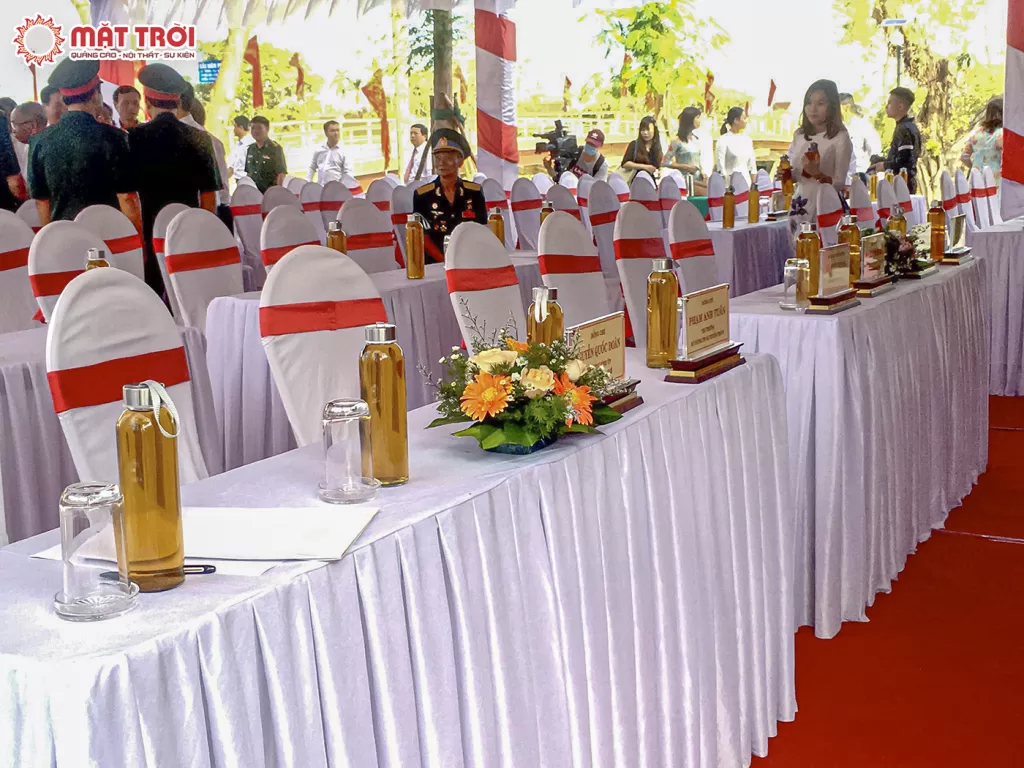 Khu vực bàn ghế đại biểu và khách mời được phủ khăn trắng kèm nơ đỏ và hoa - Sự kiện Mặt Trời: Công ty sự kiện tại Huế